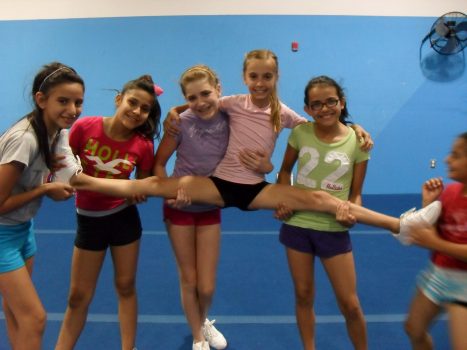 4 girls hold the 5th girl doing the splits